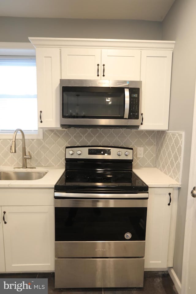 kitchen with white cabinets, appliances with stainless steel finishes, backsplash, and sink