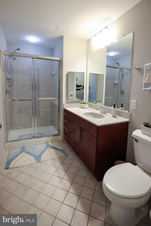 bathroom with tile patterned flooring, vanity, toilet, and an enclosed shower