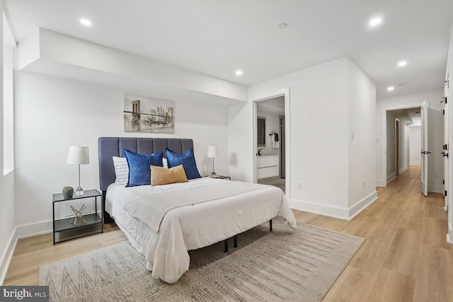 bedroom with light wood-type flooring and connected bathroom