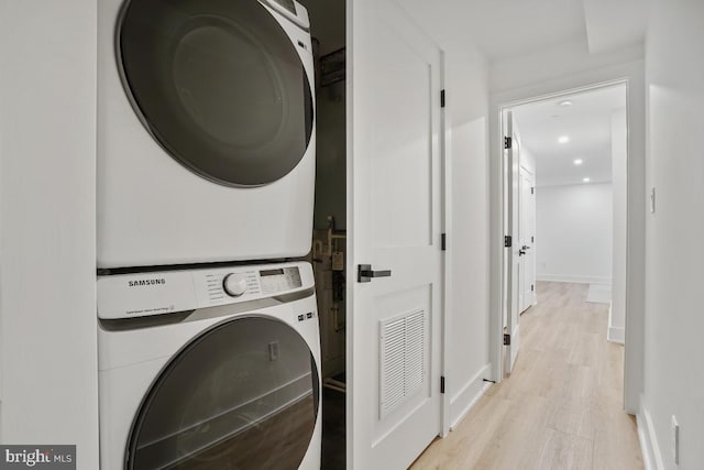 clothes washing area featuring stacked washer and dryer and light hardwood / wood-style flooring