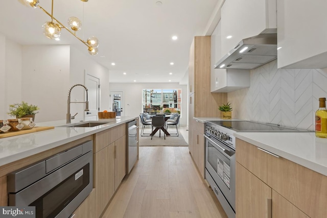 kitchen featuring sink, tasteful backsplash, light brown cabinetry, appliances with stainless steel finishes, and decorative light fixtures