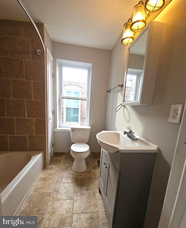 full bathroom featuring tiled shower / bath, vanity, toilet, and plenty of natural light