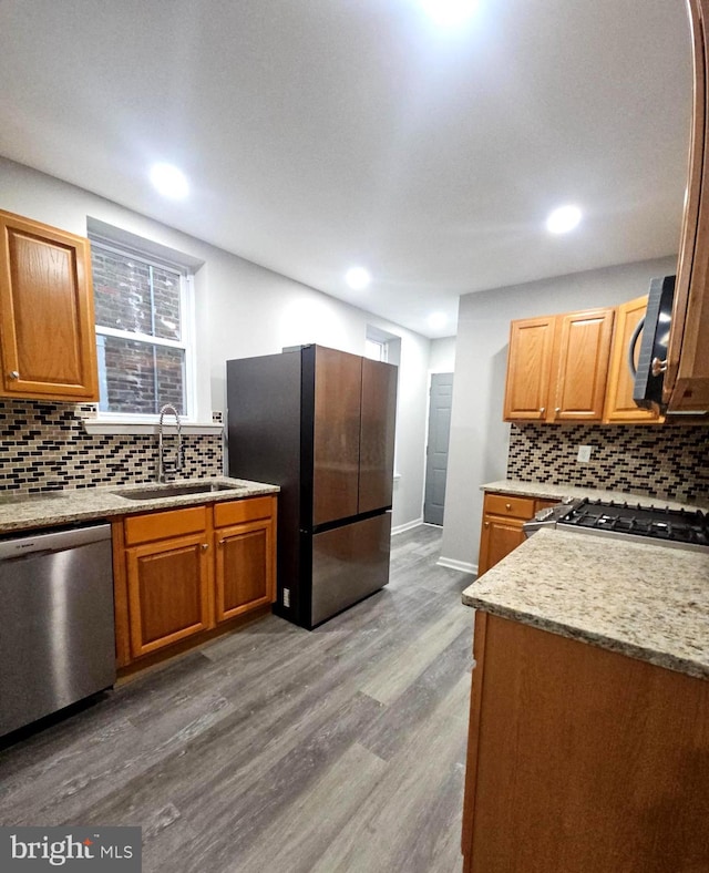 kitchen with sink, stainless steel dishwasher, stove, fridge, and light wood-type flooring