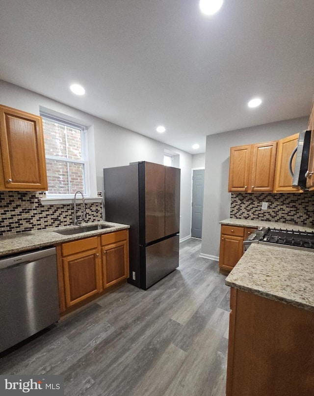 kitchen with sink, tasteful backsplash, light stone counters, dark hardwood / wood-style floors, and appliances with stainless steel finishes