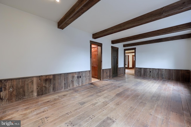 empty room featuring beam ceiling and light hardwood / wood-style flooring