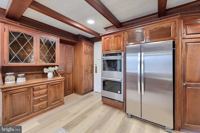 kitchen featuring beam ceiling, stainless steel appliances, and light hardwood / wood-style floors