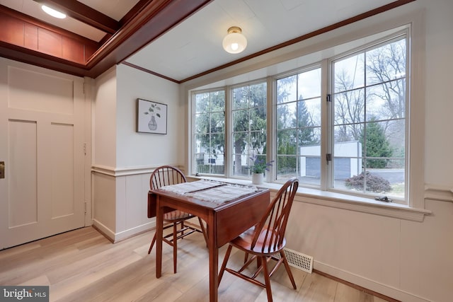 dining space with light hardwood / wood-style flooring and ornamental molding