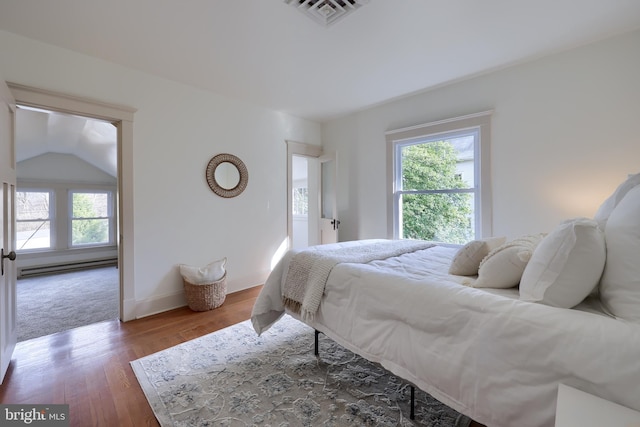 bedroom featuring dark hardwood / wood-style flooring, vaulted ceiling, and a baseboard heating unit