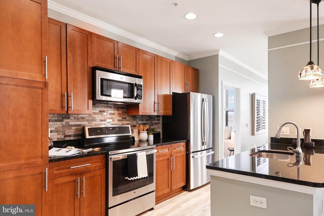 kitchen featuring stainless steel appliances, sink, tasteful backsplash, hanging light fixtures, and a kitchen island with sink