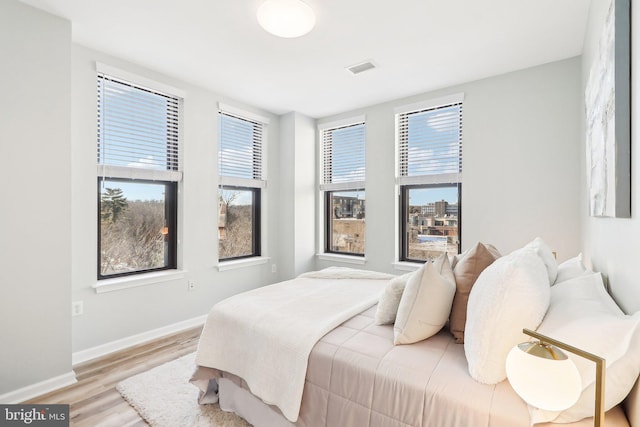 bedroom with light hardwood / wood-style flooring and multiple windows