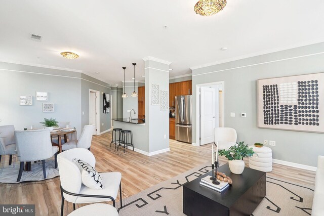 living room with sink, crown molding, and light hardwood / wood-style flooring