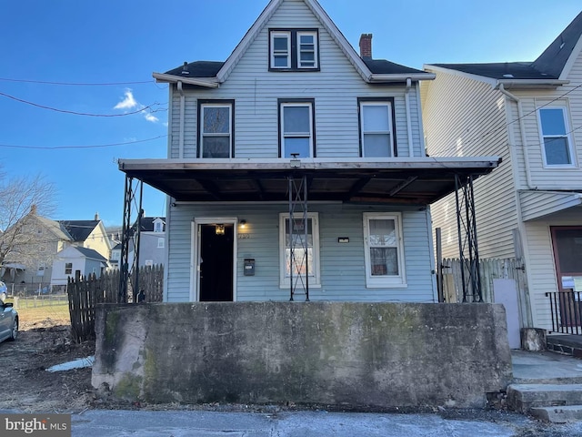 view of front of home with a porch, fence, and a chimney