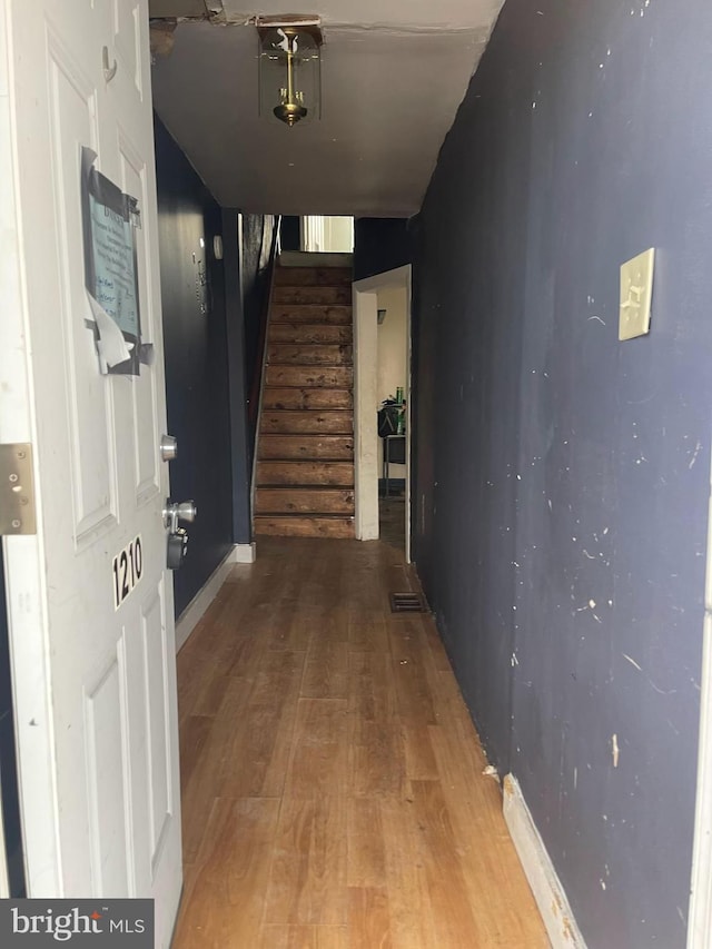 hall featuring stairs, baseboards, and wood finished floors