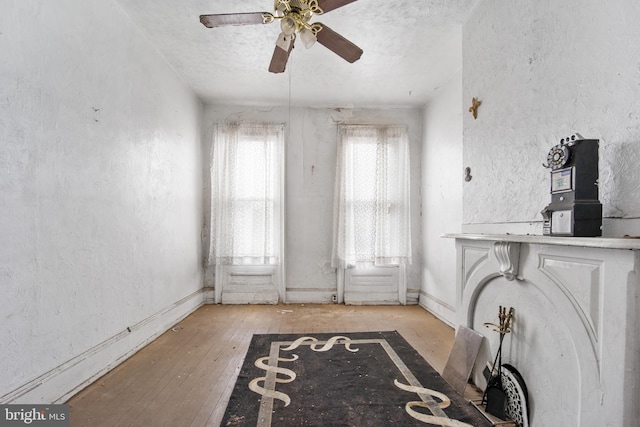 interior space featuring ceiling fan, light wood-type flooring, and a textured ceiling