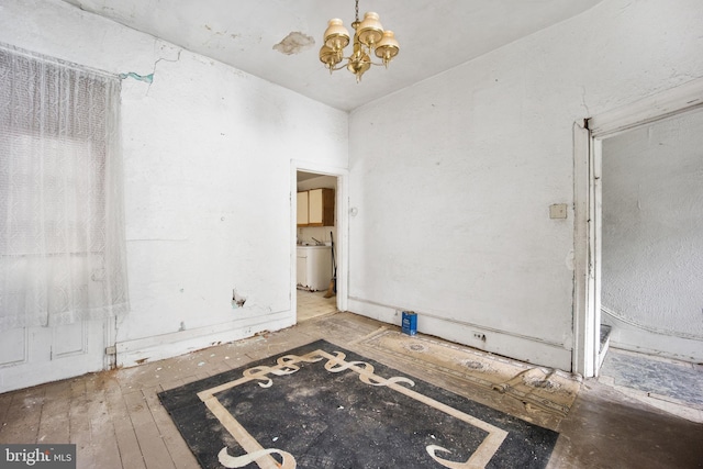 empty room featuring wood-type flooring and a notable chandelier