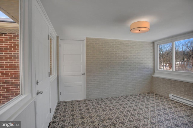 spare room with brick wall and a baseboard radiator