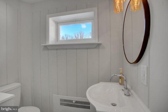 bathroom with toilet, radiator heating unit, and sink