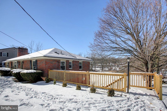 snow covered property with a wooden deck