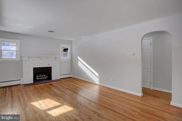 unfurnished living room featuring a brick fireplace, light wood-type flooring, and a baseboard heating unit