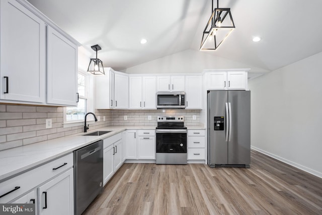 kitchen featuring hanging light fixtures, sink, white cabinets, lofted ceiling, and stainless steel appliances