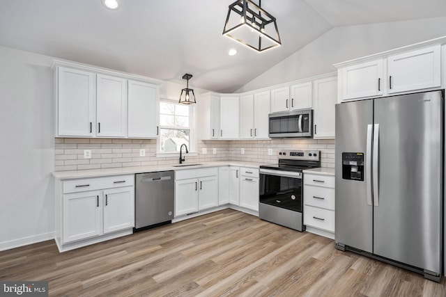 kitchen with decorative light fixtures, white cabinetry, appliances with stainless steel finishes, and vaulted ceiling