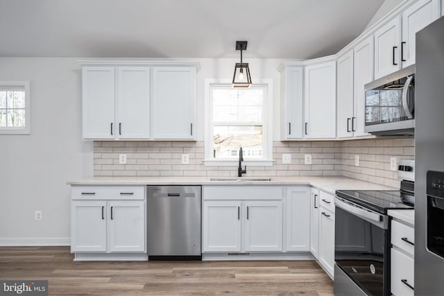 kitchen with sink, white cabinetry, appliances with stainless steel finishes, and hanging light fixtures