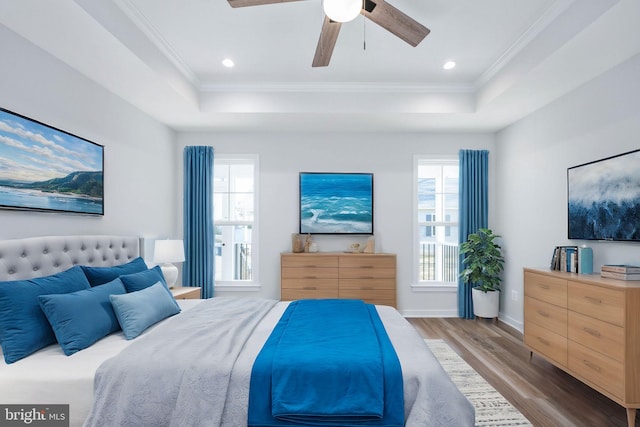 bedroom with ceiling fan, ornamental molding, light hardwood / wood-style floors, and a tray ceiling