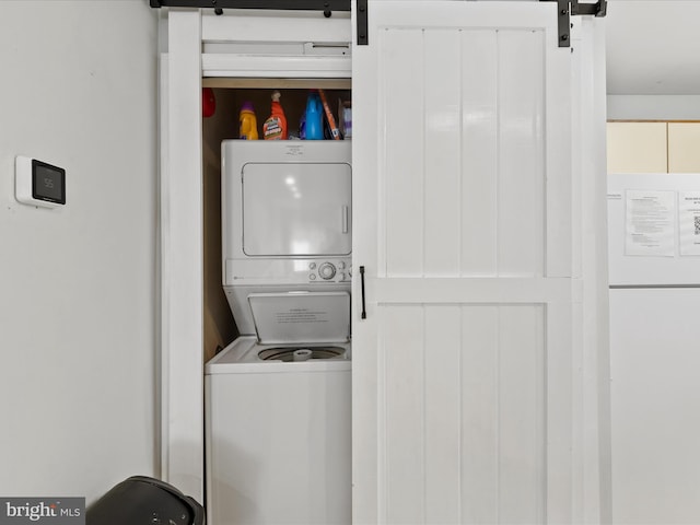 washroom featuring a barn door and stacked washer and clothes dryer