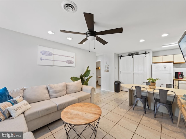 tiled living room with ceiling fan and a barn door