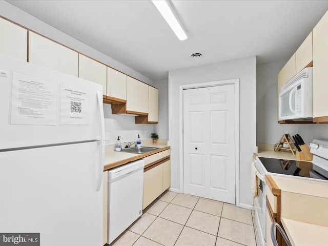 kitchen featuring white appliances, sink, and light tile patterned floors