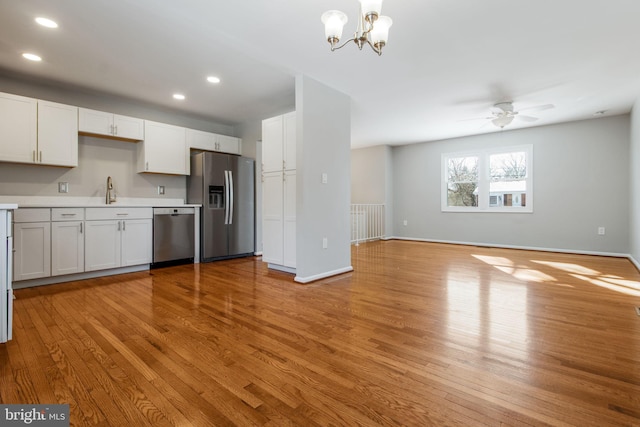 kitchen with light hardwood / wood-style flooring, white cabinets, decorative light fixtures, and appliances with stainless steel finishes