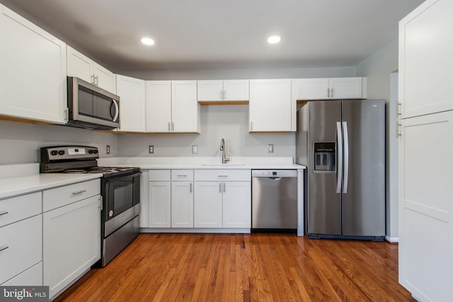 kitchen with hardwood / wood-style floors, sink, white cabinetry, and stainless steel appliances