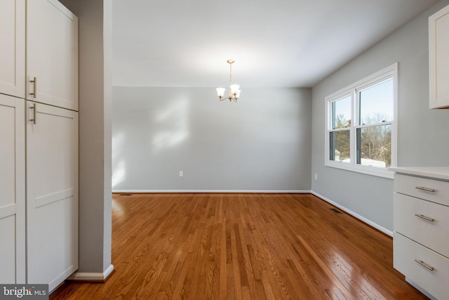 unfurnished dining area featuring light wood-type flooring and an inviting chandelier