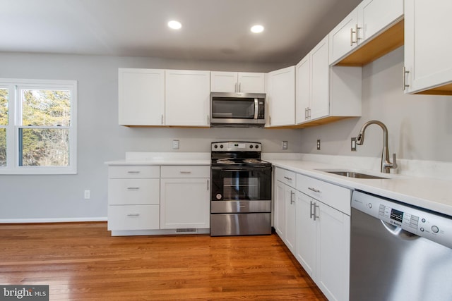 kitchen with white cabinets, sink, light wood-type flooring, and stainless steel appliances