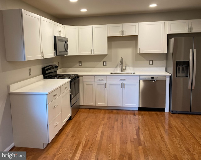 kitchen with sink, white cabinets, stainless steel appliances, and light hardwood / wood-style floors