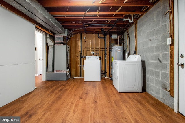 basement featuring washer and dryer, hardwood / wood-style flooring, and heating unit