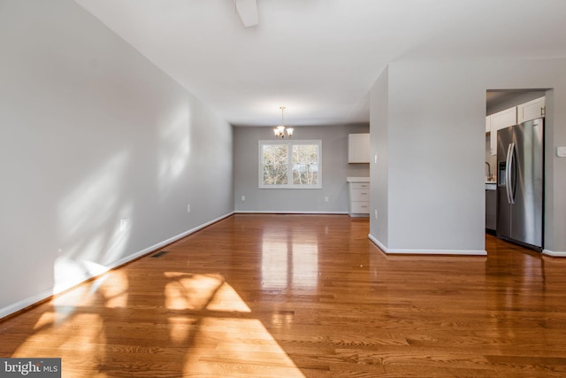 unfurnished living room featuring hardwood / wood-style floors and an inviting chandelier