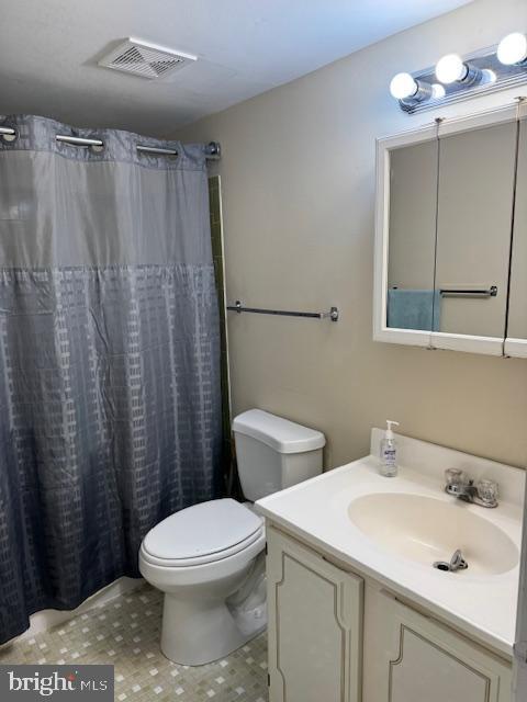 bathroom featuring toilet, vanity, and a shower with shower curtain