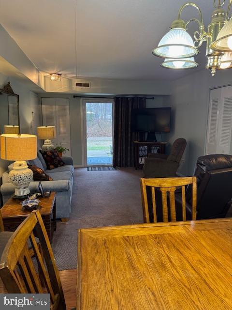 carpeted living room with a notable chandelier