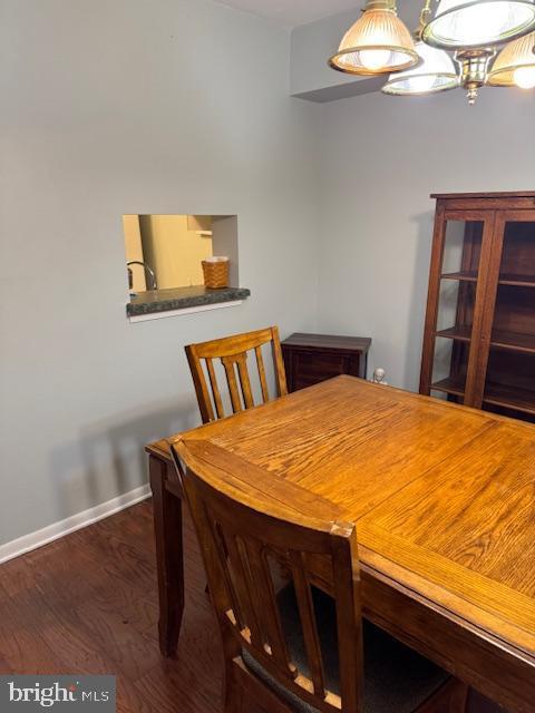 dining room with dark wood-type flooring and a chandelier