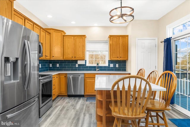 kitchen featuring stainless steel appliances, sink, light hardwood / wood-style flooring, a chandelier, and hanging light fixtures