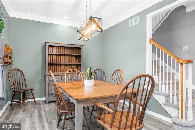 dining space with hardwood / wood-style flooring and ornamental molding