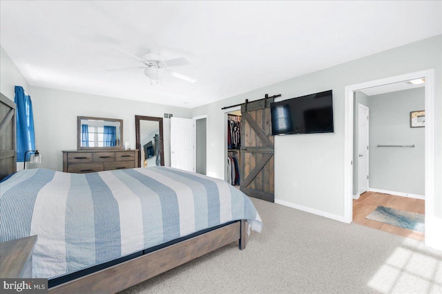 bedroom featuring a barn door, ceiling fan, and carpet floors