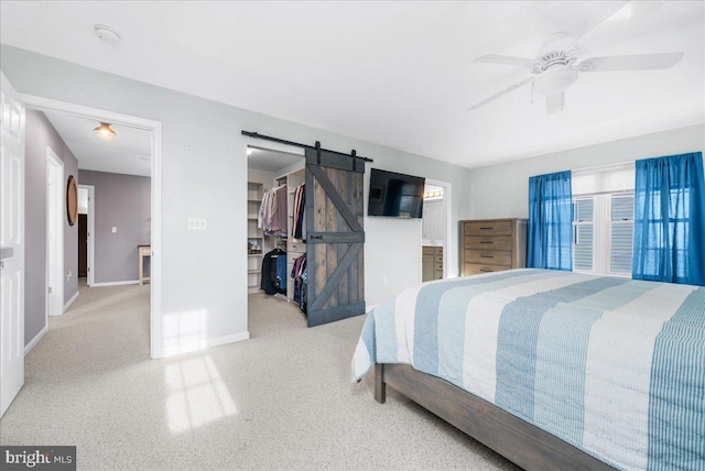 bedroom with a walk in closet, a barn door, a closet, and ceiling fan