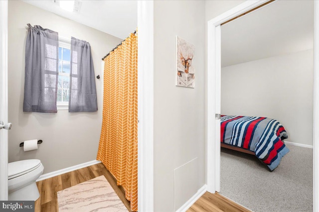 bathroom featuring hardwood / wood-style floors, toilet, and walk in shower