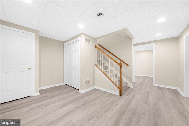 basement with a paneled ceiling and light hardwood / wood-style flooring