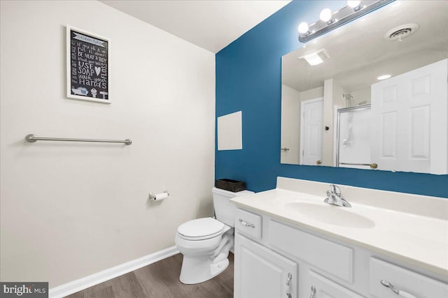 bathroom with hardwood / wood-style floors, vanity, toilet, and walk in shower