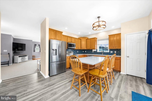 kitchen featuring appliances with stainless steel finishes, sink, light hardwood / wood-style flooring, a chandelier, and a center island