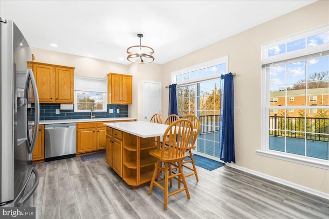 kitchen featuring backsplash, hanging light fixtures, appliances with stainless steel finishes, a kitchen island, and a chandelier