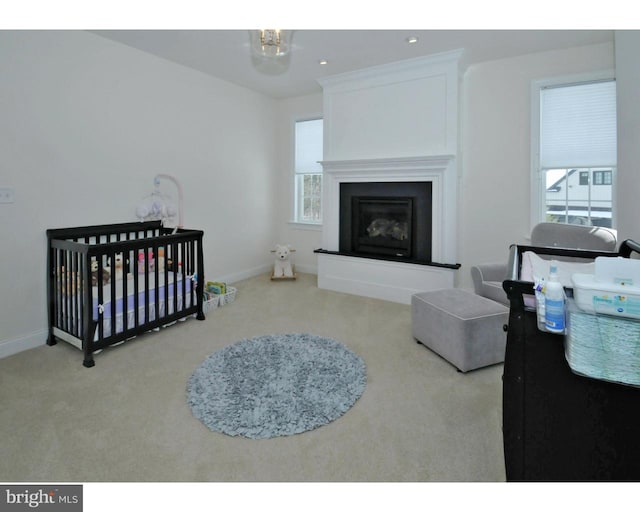 carpeted bedroom featuring multiple windows and a nursery area